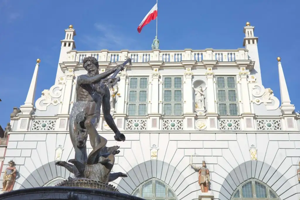 Der Neptunbrunnen in Danzig, ein historischer Brunnen mit einer Neptun-Statue, umgeben von Touristen und prächtigen Gebäuden in der Altstadt.