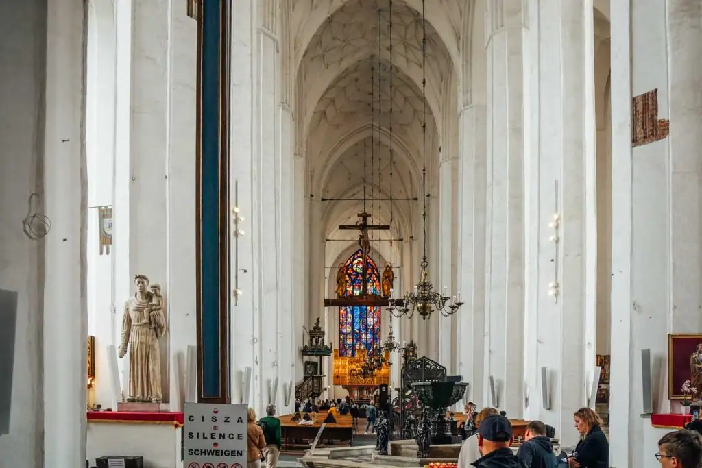 Innenansicht der Marienkirche in Danzig, mit hohen gotischen Gewölben, kunstvollen Altären und historischen Kunstwerken.