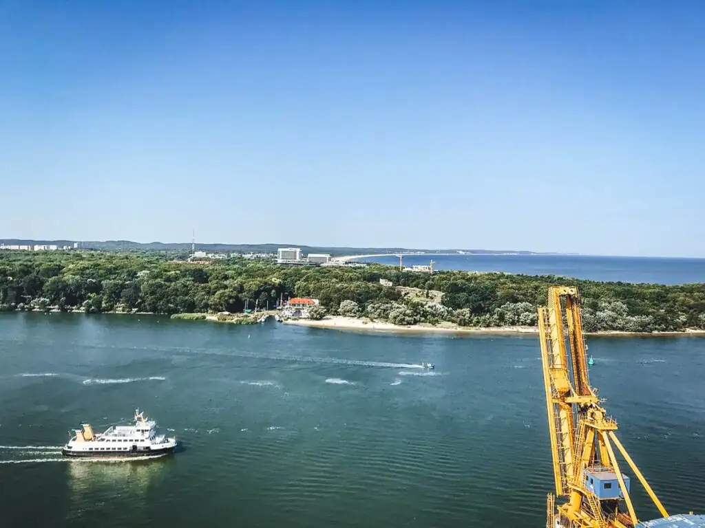 Blick vom Leuchtturm in Swinemünde Richtung Usedom: Eine atemberaubende Aussicht auf die grüne Landschaft der Insel Usedom, die sanft ins Meer übergeht. Die weite Küstenlinie und das Blau der Ostsee verbinden sich mit der natürlichen Schönheit der Region.