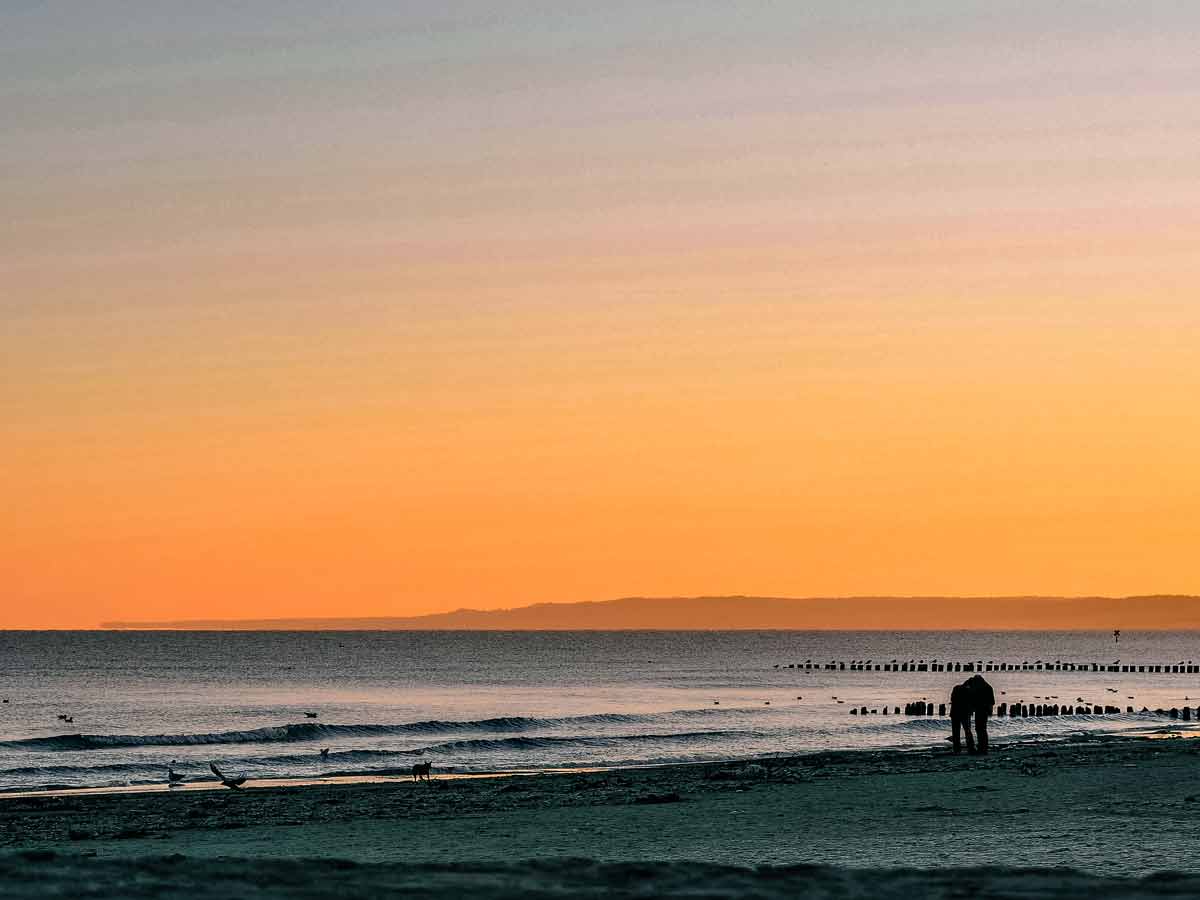 Strand von Ustka im Sonnenuntergang mit Buhnen