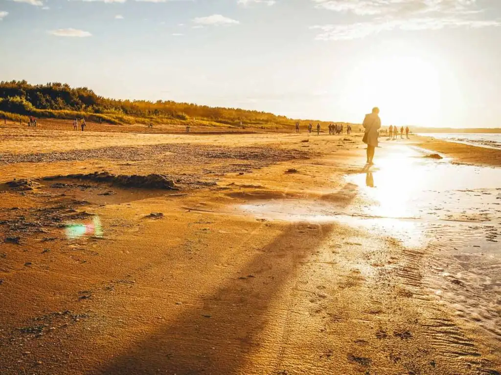 Urlauber am breiten Strand der Polnischen Ostsee genießen die letzen Sonnenstrahlen des Tages.