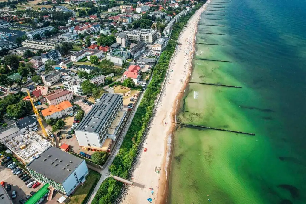 Luftaufnahme des Strandes von Ustronie Morskie an der polnischen Ostsee mit Sandstrand und Wellen.