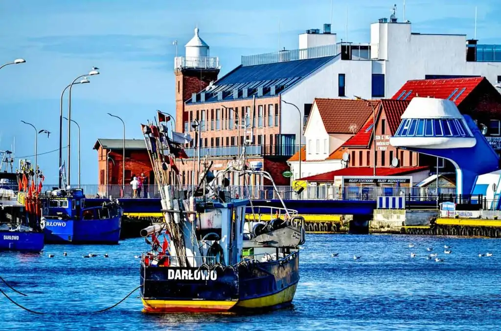 Hafen von Darłowo mit Fischerbooten, Promenade und Blick auf die Polnische Ostsee.