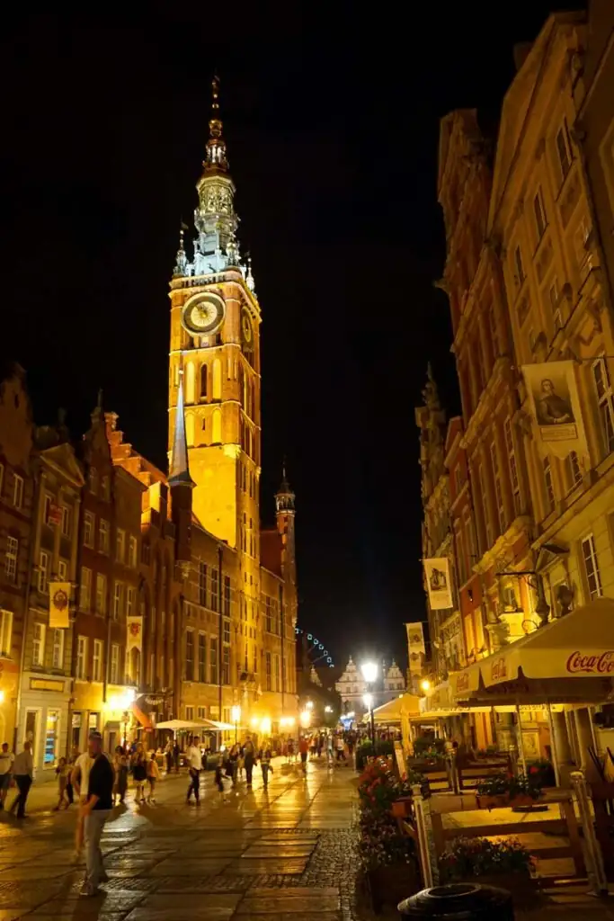 Beleuchtetes Rechtstädtisches Rathaus in Danzig bei Nacht mit sichtbarer Turmuhr.