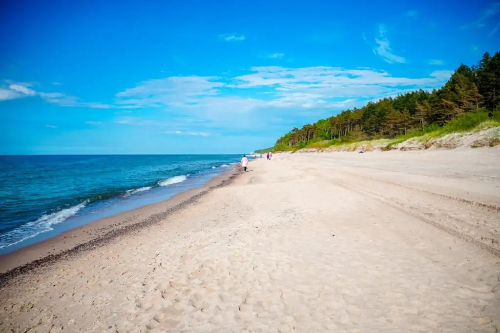 Weitläufiger Sandstrand von Pobierowo mit wenigen Spaziergängern und der Ostsee im Hintergrund.