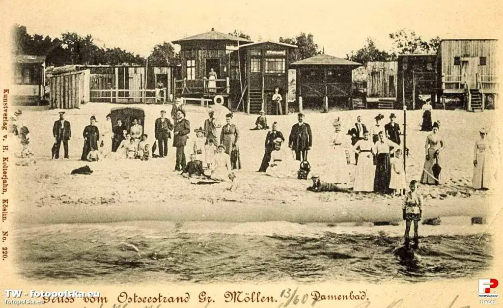 Historische Strandaufnahme von Mielno mit Badegästen und einfachen Holzbauten auf einer alten Postkarte