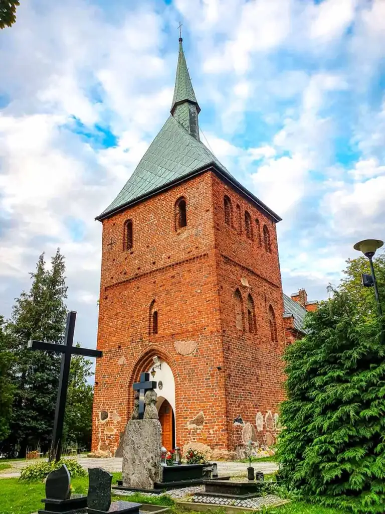 Kirche der Verklärung des Herrn in Mielno, Backsteinbau mit neugotischen Elementen zwischen Bäumen