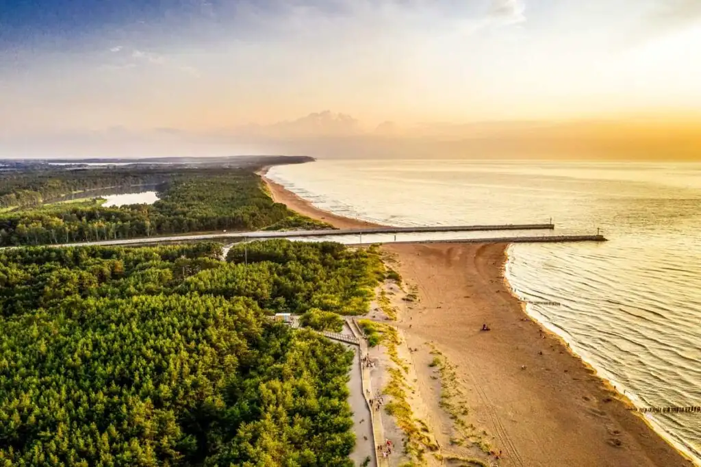 Drohnenaufnahme vom Strand in Dziwnów mit Flussmündung und Wellenbrechern