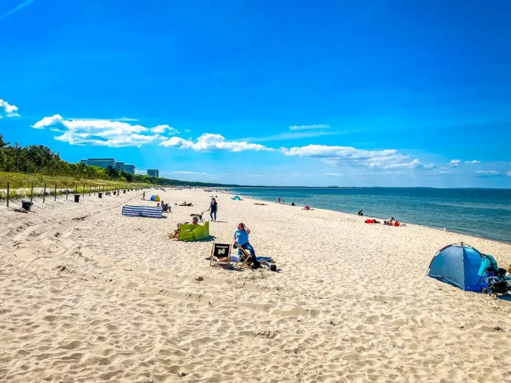 Strand von Misdroy in westlicher Richtung – breiter Sandstrand, Ostsee und Dünenlandschaft im Hintergrund.
