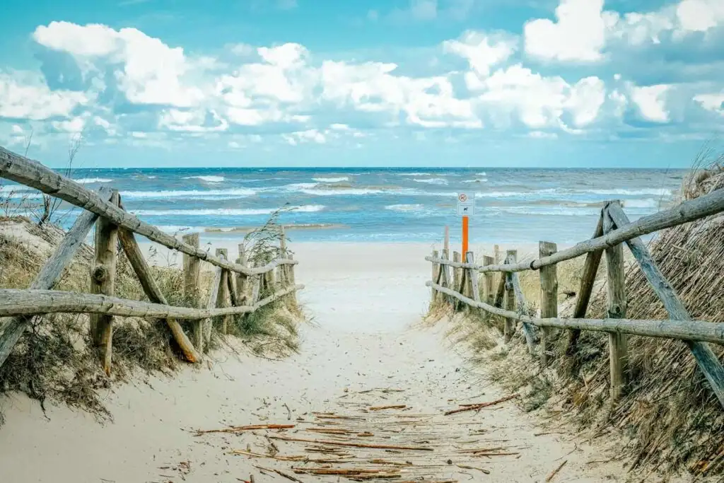 Sandiger Weg mit Holzgeländern links und rechts führt in Dębki durch die Dünen zum Strand und zur Ostsee.