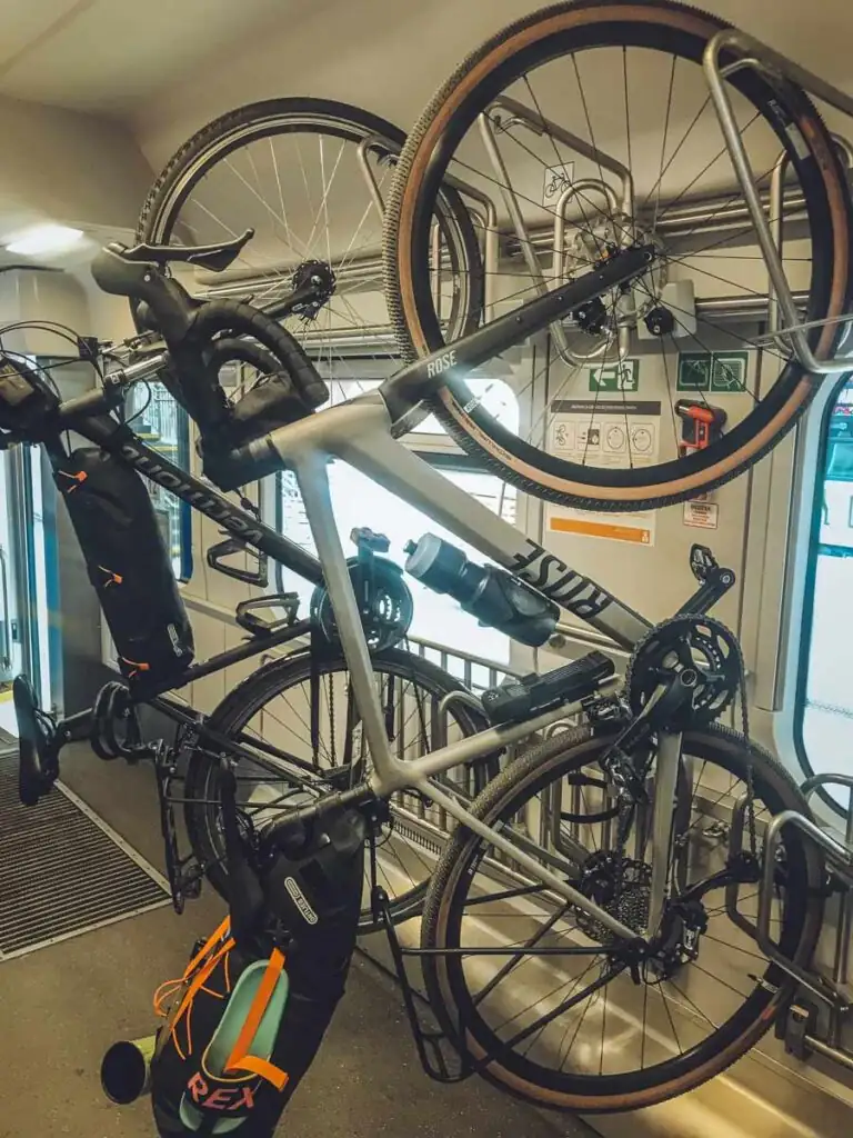 Zwei Fahrräder hängen an den vorgesehenen Haken in einem polnischen Intercity-Wagen; daneben der Gang und Türen zum Einstiegsbereich.