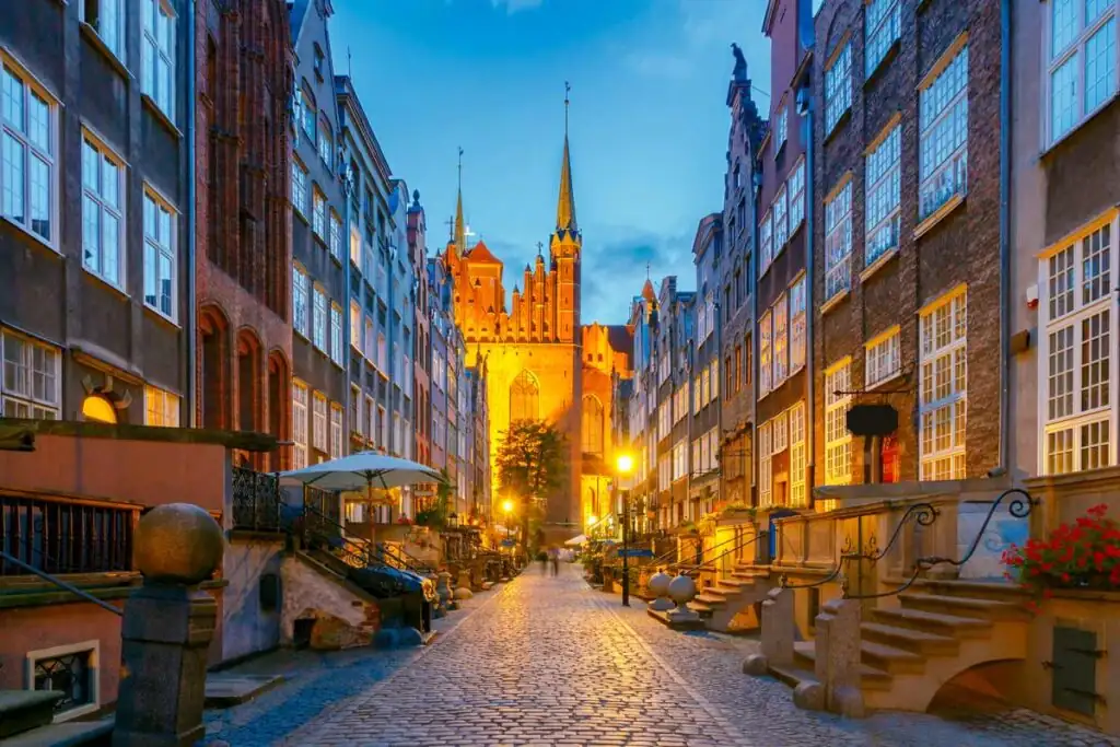Frauengasse (Ulica Mariacka) in Danzig bei Abendlicht mit beleuchteten Laternen, Kopfsteinpflaster und historischen Hausfassaden.