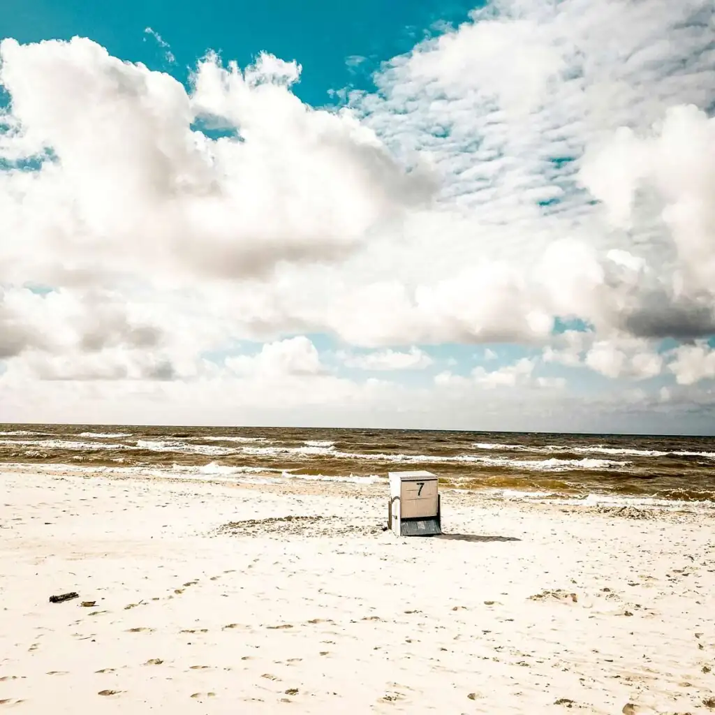 Strandkorb steht auf dem breiten, sonnigen Sandstrand von Dębki mit Blick auf die Ostsee.
